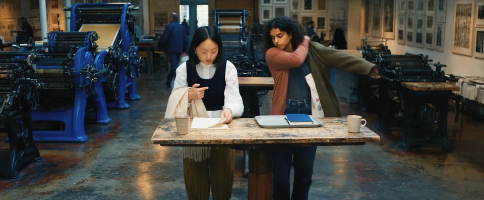 Two colleagues finish a discussion in a print workshop while one uses Interface, in a frame from the teaser