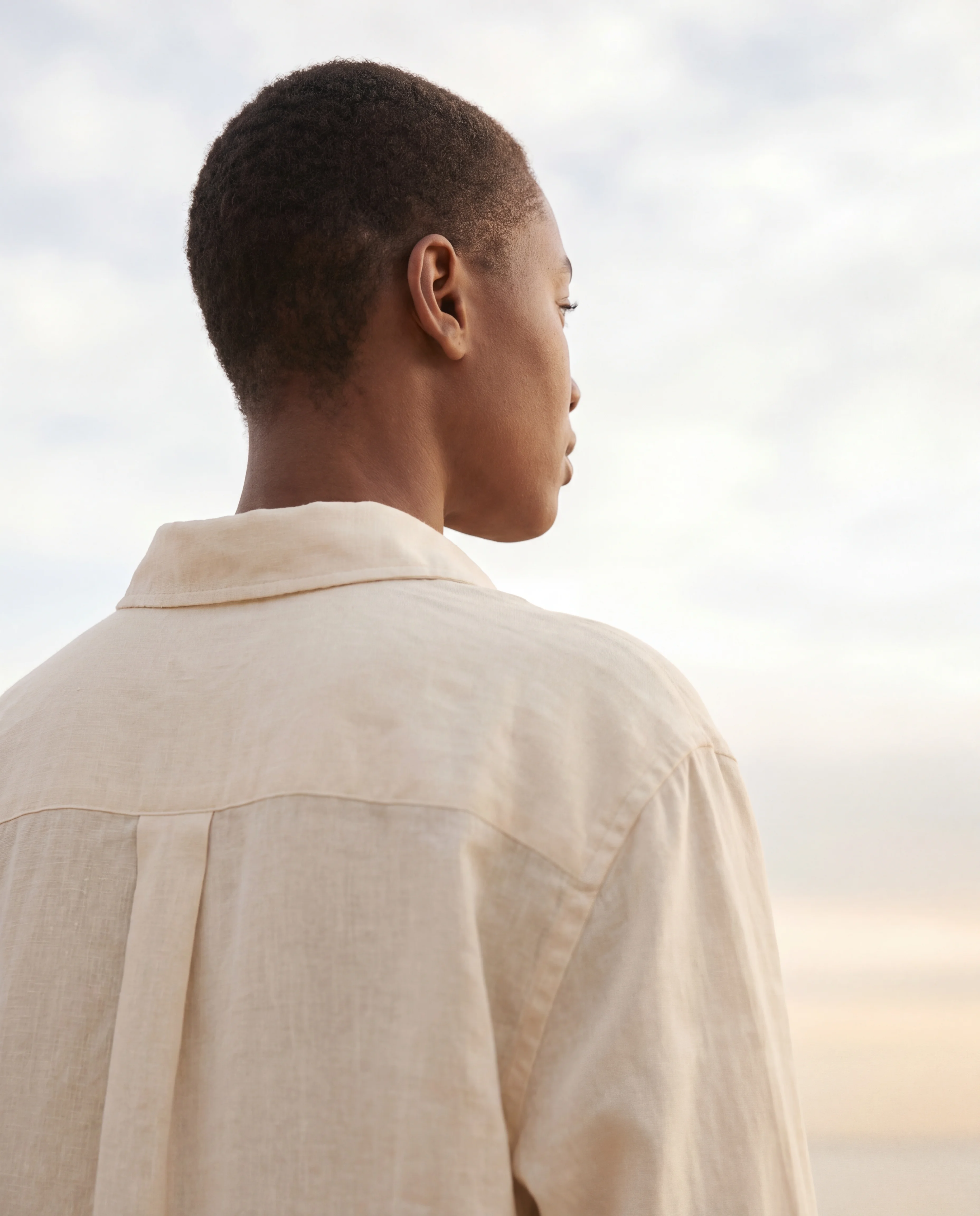 Figure with a HumanPod, calm contemplative pose against soft sky